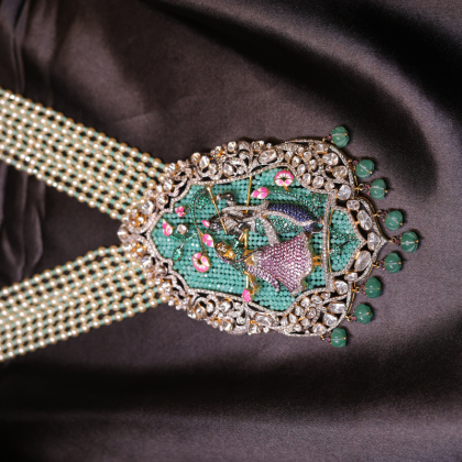 A handcrafted Radha-Krishna Meenakari necklace with pearls, emeralds, and uncut diamonds in divine detail.